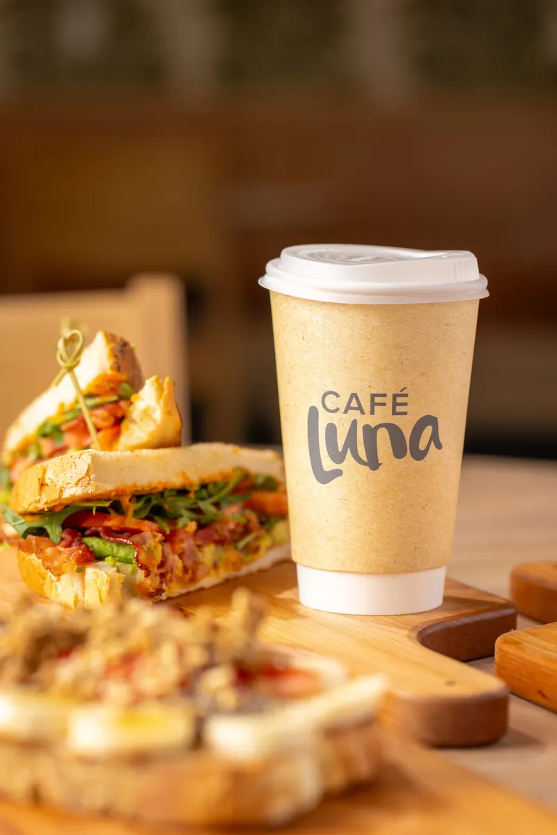 Sandwich on a board beside a Café Luna coffee cup